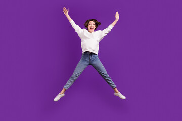 Fototapeta na wymiar Full size photo of young smiling carefree girl jumping raise hands wear white sweatshirt isolated on purple color background