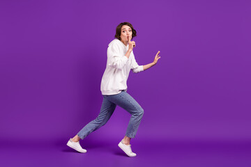 Fototapeta na wymiar Full size photo of young serious girl show shut-up gesture running away hiding isolated on purple color background