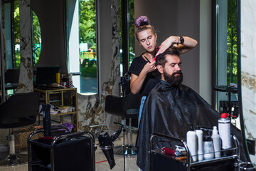 Portrait of stylish guy and Barber master with scissors and brush, barbershop