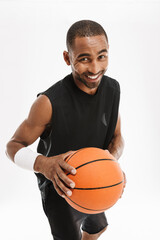 Young black sportsman smiling at camera while posing with basketball