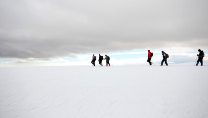 Fototapeta na wymiar Group of mountaineers walking trough the mountains covered with snow...