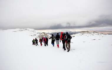 Group of mountaineers walking trough the mountains covered with snow...