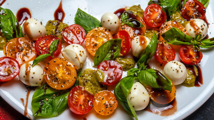Caprese salad. Healthy meal with cherry tomatoes, mozzarella balls, spices, fresh rocket and basil.