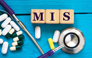 MIS - acronym on wooden cubes on a blue background with a stethoscope and tablets © Zhanna