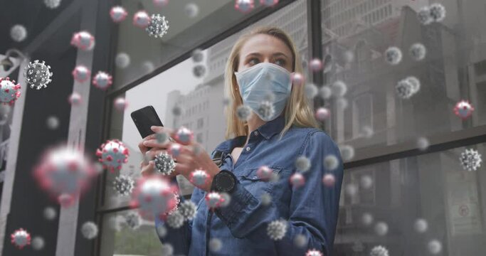 Animation of virus cells over caucasian female wearing face mask, using smartphone