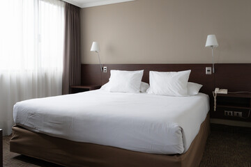 Bright bedroom with king size bed and night lamps on sides. Hotel reservation, interior design decoration concepts