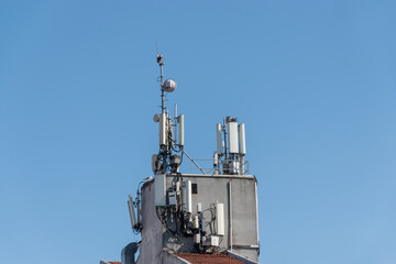 Fototapeta na wymiar GSM antenna on the building roof front of the blue sky