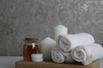 Obraz na płótnie Canvas Spa relax massage home care for soy body. White candles towels oil in a jar bottle scrub on a white gray background with space for text. Beauty parlour