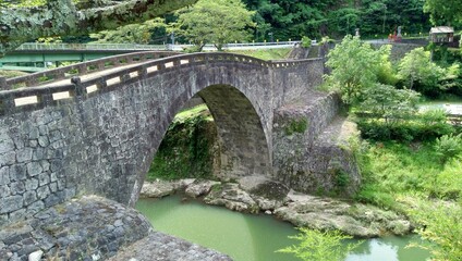 Fototapeta na wymiar An arched bridge made of stone over a river flowing between mountains