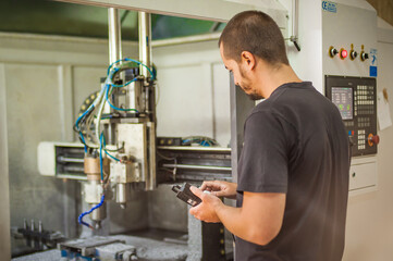 Engineer worker technician operating with CNC milling metal engraving machine in factory workshop.