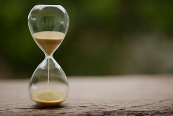Sand clock , Hourglass as time passing on green nature background , Life time concept