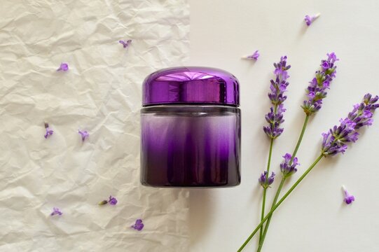 Lavender anti-wrinkle cosmetic serum in a purple bottle with lavender flowers  on white  background top view closeup.