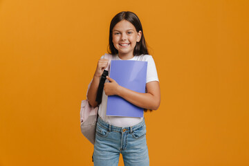 White brunette girl laughing while posing with backpack and exercise book