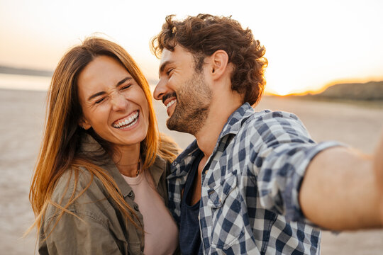 White young couple laughing and hugging while taking selfie photo