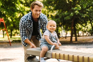 Fototapeta na wymiar White father smiling while playing with his son at playground