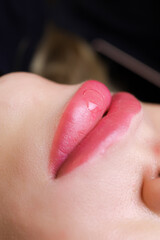 a drop of oil on the lips of the model after performing permanent lip makeup