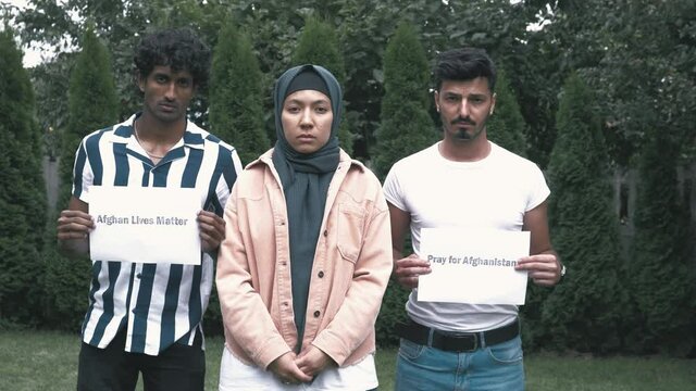 Group of young people showing protest signs to save Afghanistan, pray for Afghanistan. Young afghan woman in hijab and men holding signs to protect afghan people lives. Afghan lives matter 