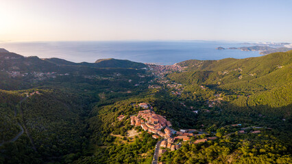 Obraz premium Aerial Drone Panorama of mountain old town Marciana on the islands of Elba Italy with green trees and the mediterranean sea ocean in the background