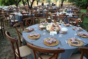 Runde gedeckte Tische mit blauen Tischdecken und Blumenschmuck für eine türkische Hochzeit im...