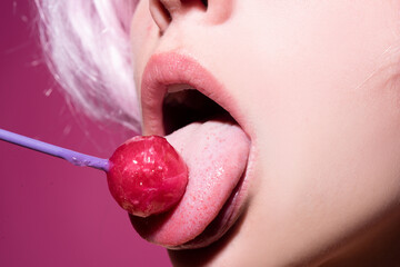 Licking candy. Lollipop model. Woman lips sucking a candy. Glamor sensual model with red lips eat...