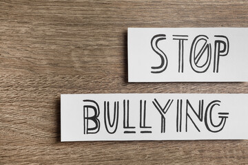 Paper cards with text Stop Bullying on wooden table, flat lay