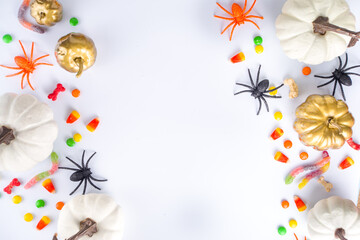 Fototapeta na wymiar Happy Halloween day holiday background. Flat lay with sweets and decorations for kids party, bucket pack with spiders, candy sweets, bat, on white table copy space top view frame