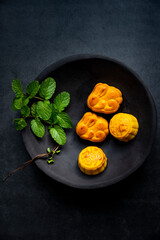 The mooncakes on a plate isolated on  dark gray background. Traditional Chinese Pastry, mid-autumn Moon cake, souffle.