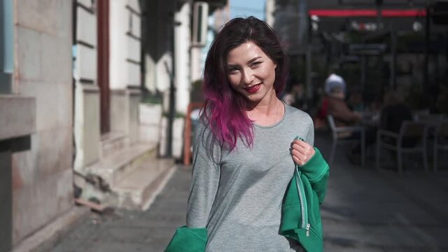 fashionable Girl smiling and posing and enjoying herself. Close-up portrait of joyful young hipster woman with bright hair walking through the summer city street. People and style concept.