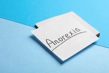 Note papers with word Anorexia on light blue background, closeup