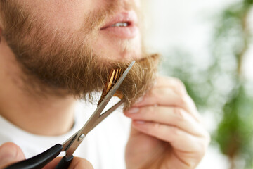 Close up of Handsome man in white t-shirts cutting beard, moustache personally himself