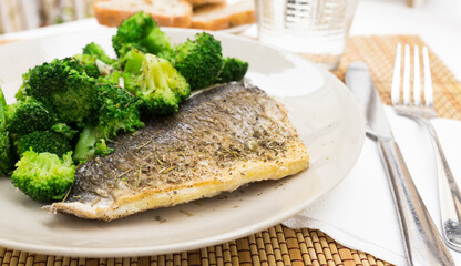 dish of fried dorado fish fillet with boiled broccoli