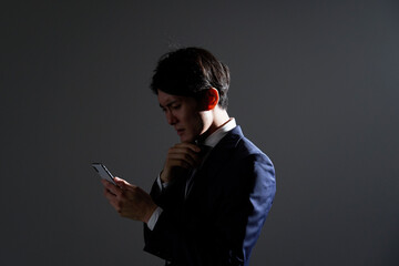 ビジネスマン　考える　スマホ