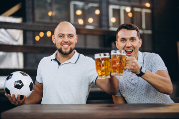 Friends drinking beer together at pub and watching football