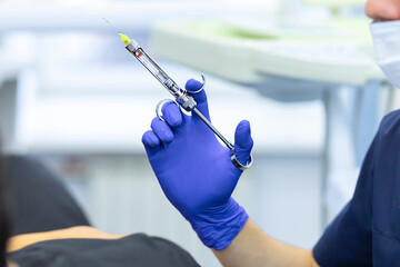 dental anesthesia syringe in hand of dentist. doctor doing anesthesia to patient. soft focus.