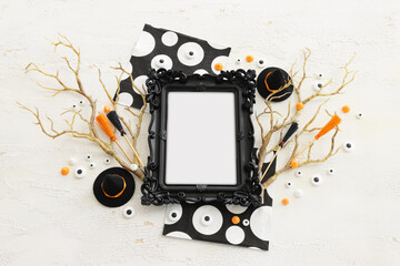 holidays image of Halloween. witcher hat, broom, bare trees, photo frame over white wooden table