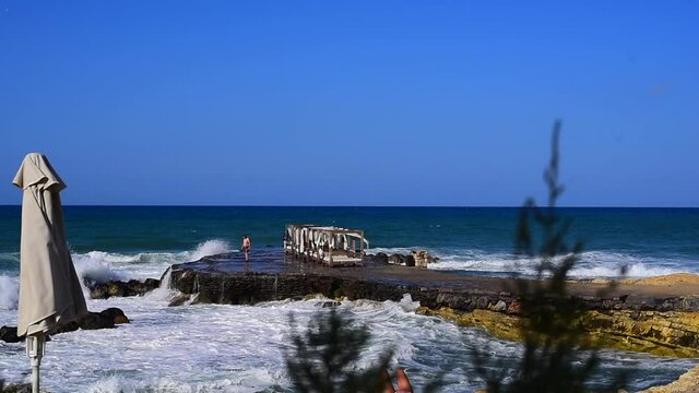 HERSONISOS, GREECE - Aug 09, 2021: The strong waves hitting the rocks in Hersonisos, Crete in Greece.