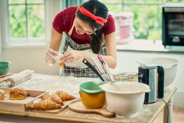 Fototapeta na wymiar Asian young female chef cooking brake egg into flour for bakery bread kitchen