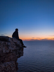 a man sits on a rock by the sea