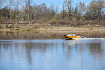 people in life jackets float on the river in a motor boat. Early spring, warm sunny day
