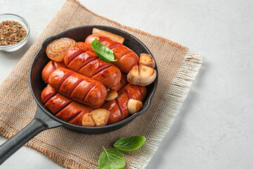 Frying pan with fried sausages on a light background. Side view, copy space