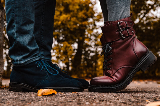 Feet of couple. Man and woman is standing opposite each other. Close-up of blue suede shoes and burgundy leather boots on tiptoe. Close-up.
