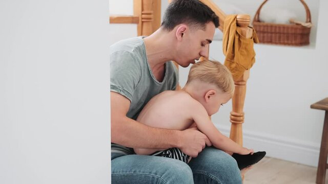 A father putting socks on his son at home