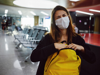 woman with yellow backpack sitting at the airport waiting discontent