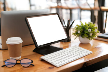 Photo of white screen digital tablet with a handle on a wooden table surrounded by personal equipment.