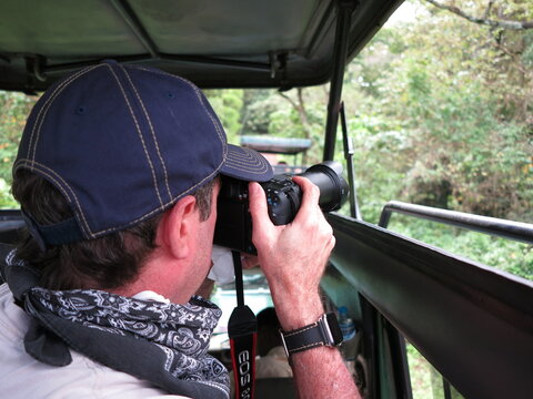 man in a jeep taking pictures on safari
