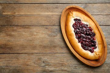 Delicious sweet cottage cheese pastry with cherry jam on wooden table, top view. Space for text
