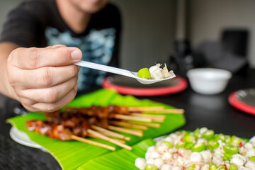 A man gets a spoonful of raw scallops and chili. Sampling Kinilaw na Scallops.