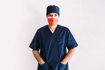 Male nurse, doctor or veterinarian wearing red mask and dark blue uniform in hospital, hands in pockets, smiling. Medicine, hospital and healthcare concept.