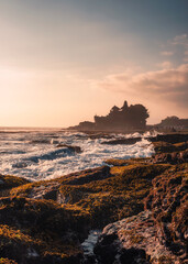 Pura Tanah Lot temple on clifftop and wave hitting on sunset beach in Bali