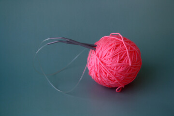 Women's hobby. Crochet and knitting. Pink yarn and crochet needles on the table.